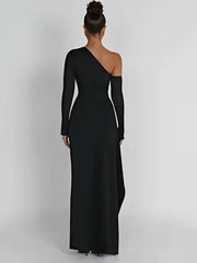 Black one-shoulder maxi dress with deep side split, ruffle detail, and detachable sleeve, crafted from crepe fabric.