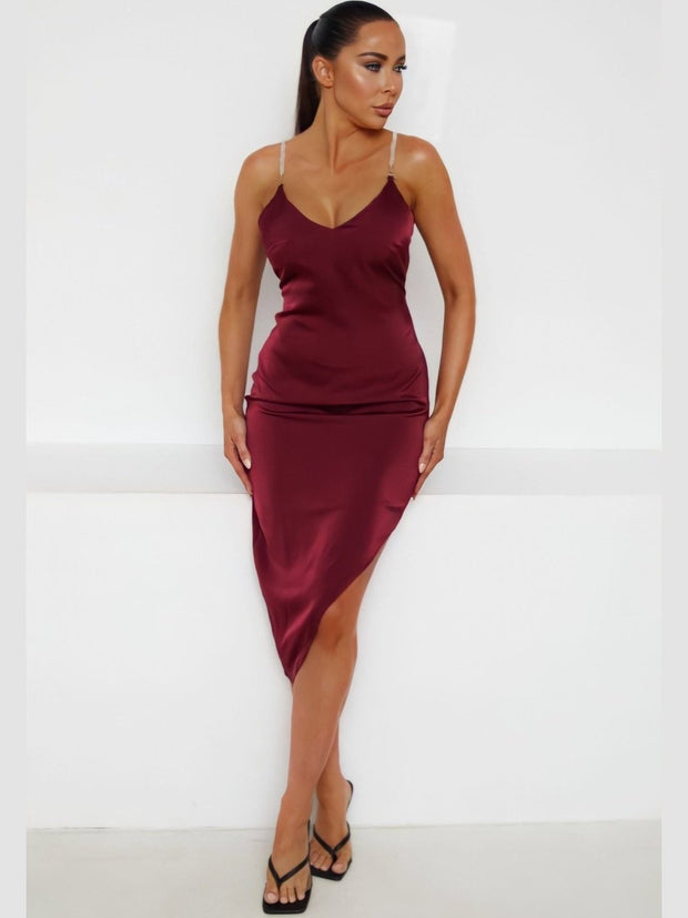 The Kendra Burgundy Satin Plunge Diamanté Strap Bodycon Midi Dress is a stunning and glamorous garment designed to make a statement. It combines luxurious materials, a seductive silhouette, and sparkling details to create a captivating look.